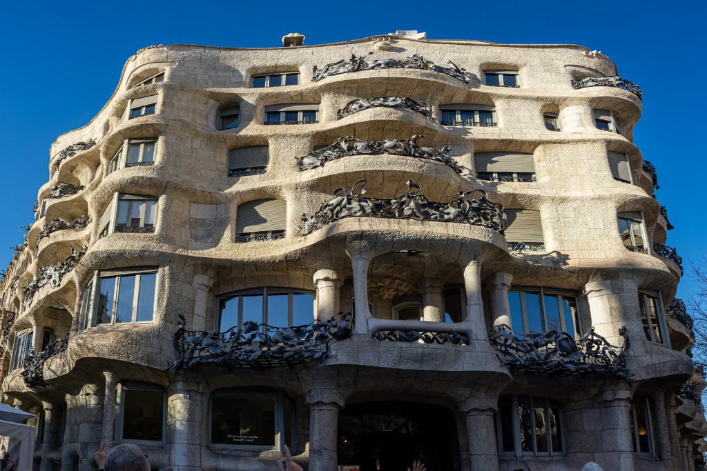 Vista frontal de la Casa Milà, también conocida como La Pedrera, un icónico edificio modernista diseñado por Antoni Gaudí en el Passeig de Gràcia de Barcelona, con su distintiva fachada ondulante y balcones de hierro forjado.
