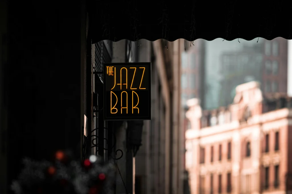 El cartel de neón de un bar de jazz, con un fondo urbano a la distancia.