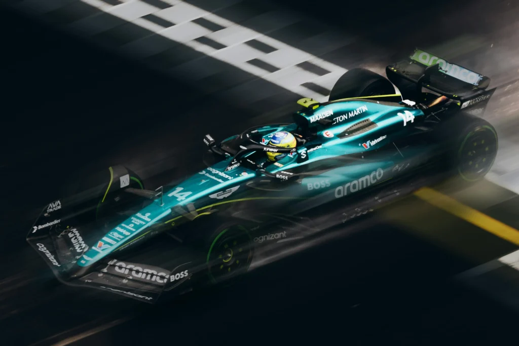 Aston Martin Formula 1 car crossing the finish line at high speed during a night race