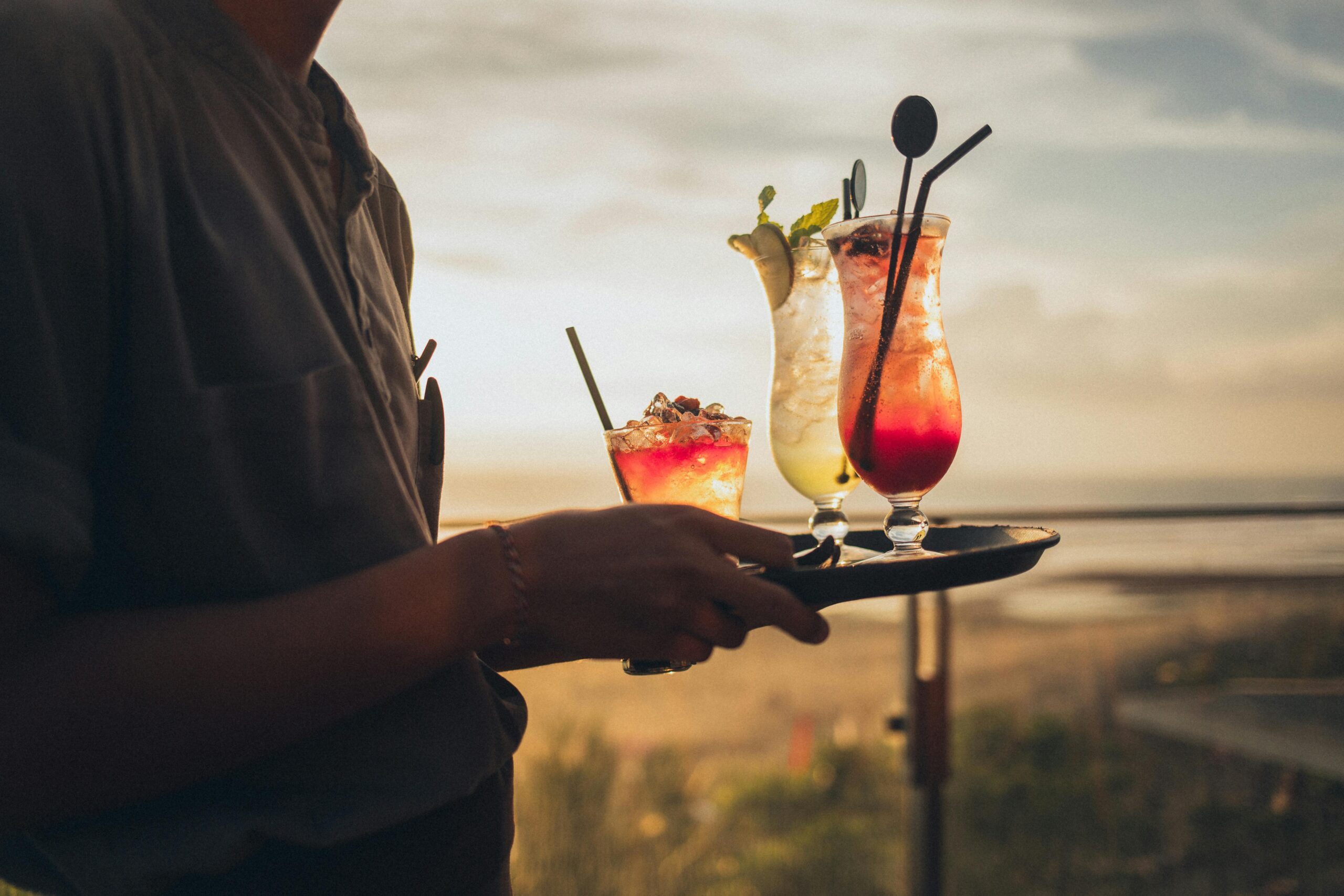 Free Standing Man Wearing Gray Shirt Holding Tray With Drinks during Golden Hour Stock Photo