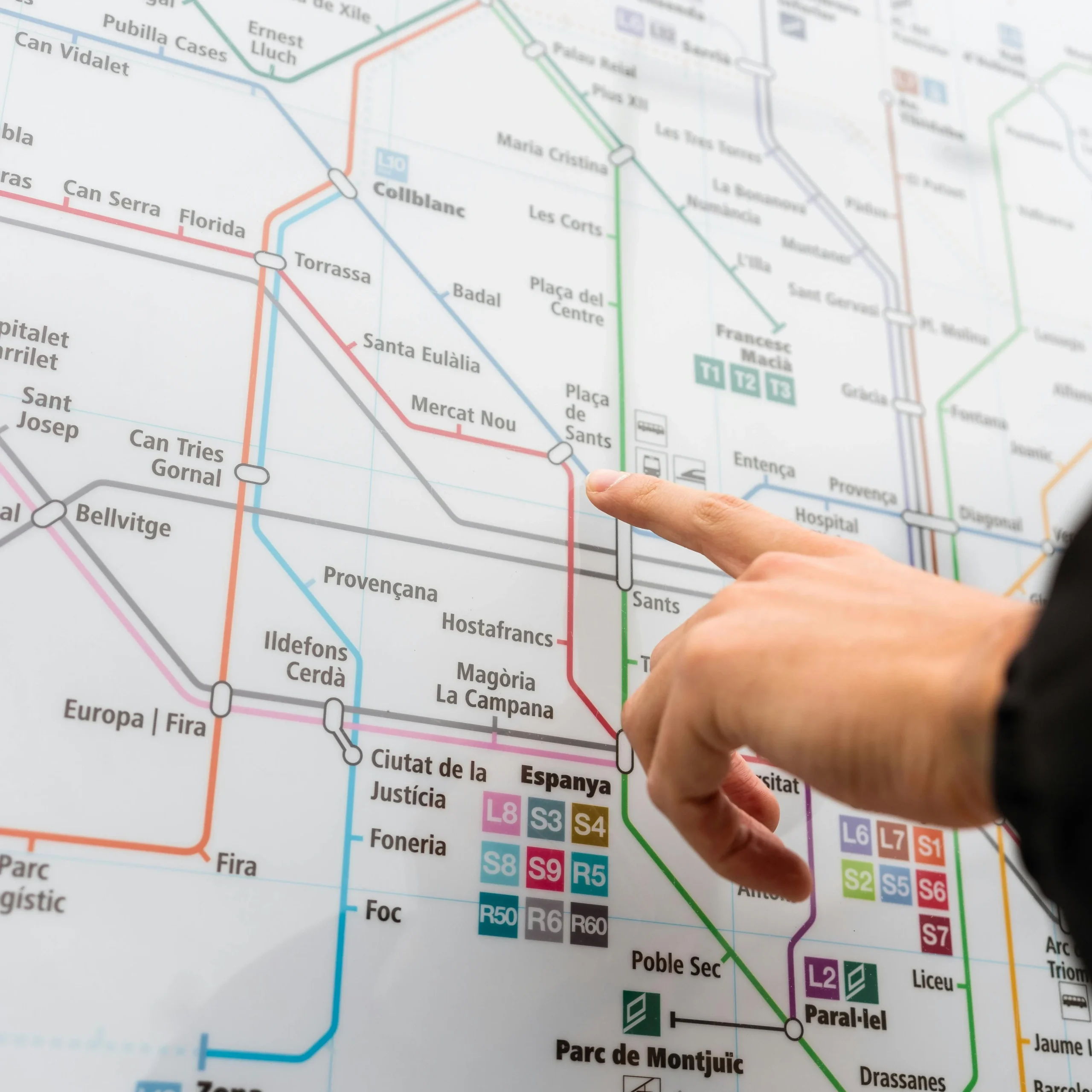 A hand pointing at the Barcelona metro map, highlighting key transport connections in the city.