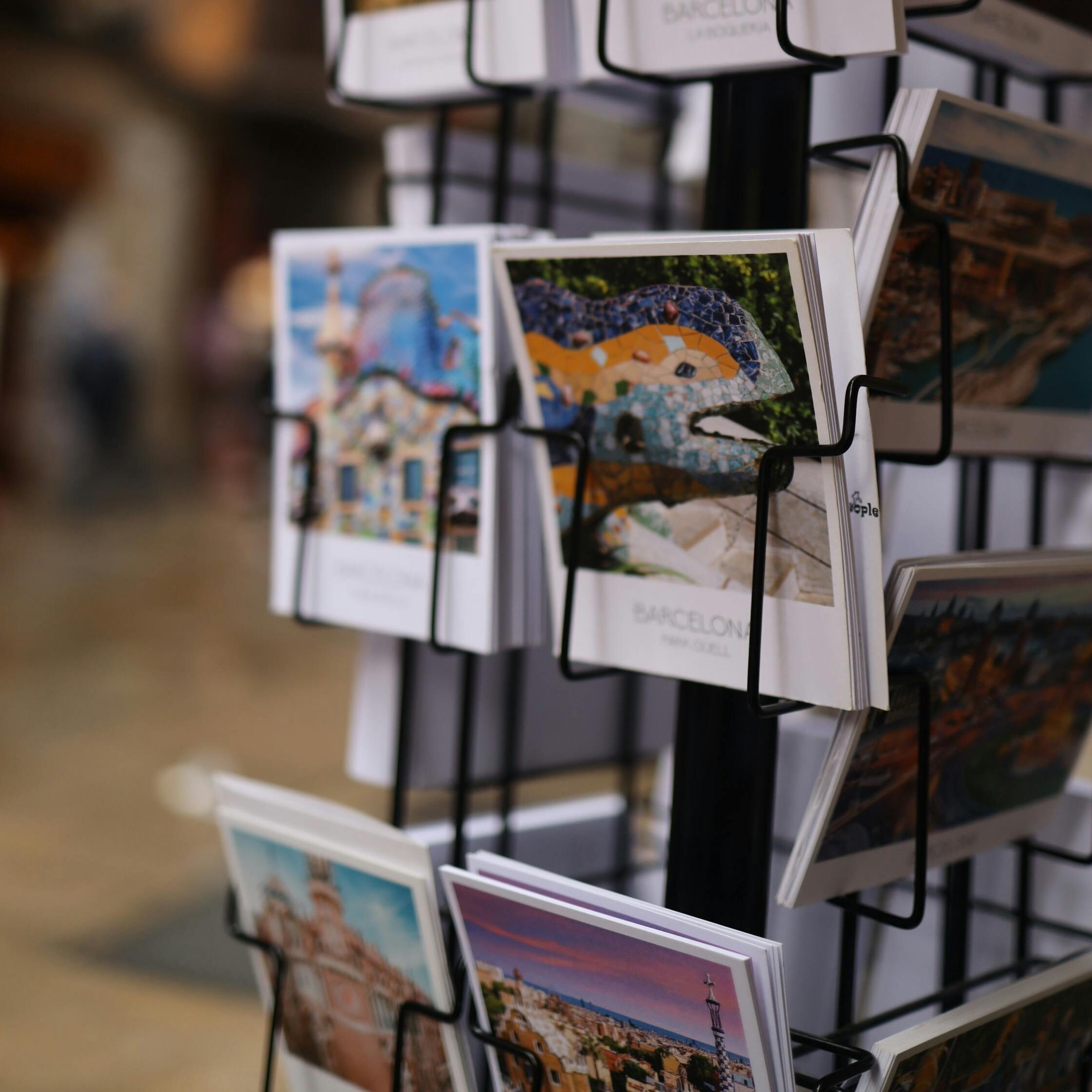 A rack filled with postcards showcasing famous Barcelona landmarks like the Sagrada Familia and Park Güell.