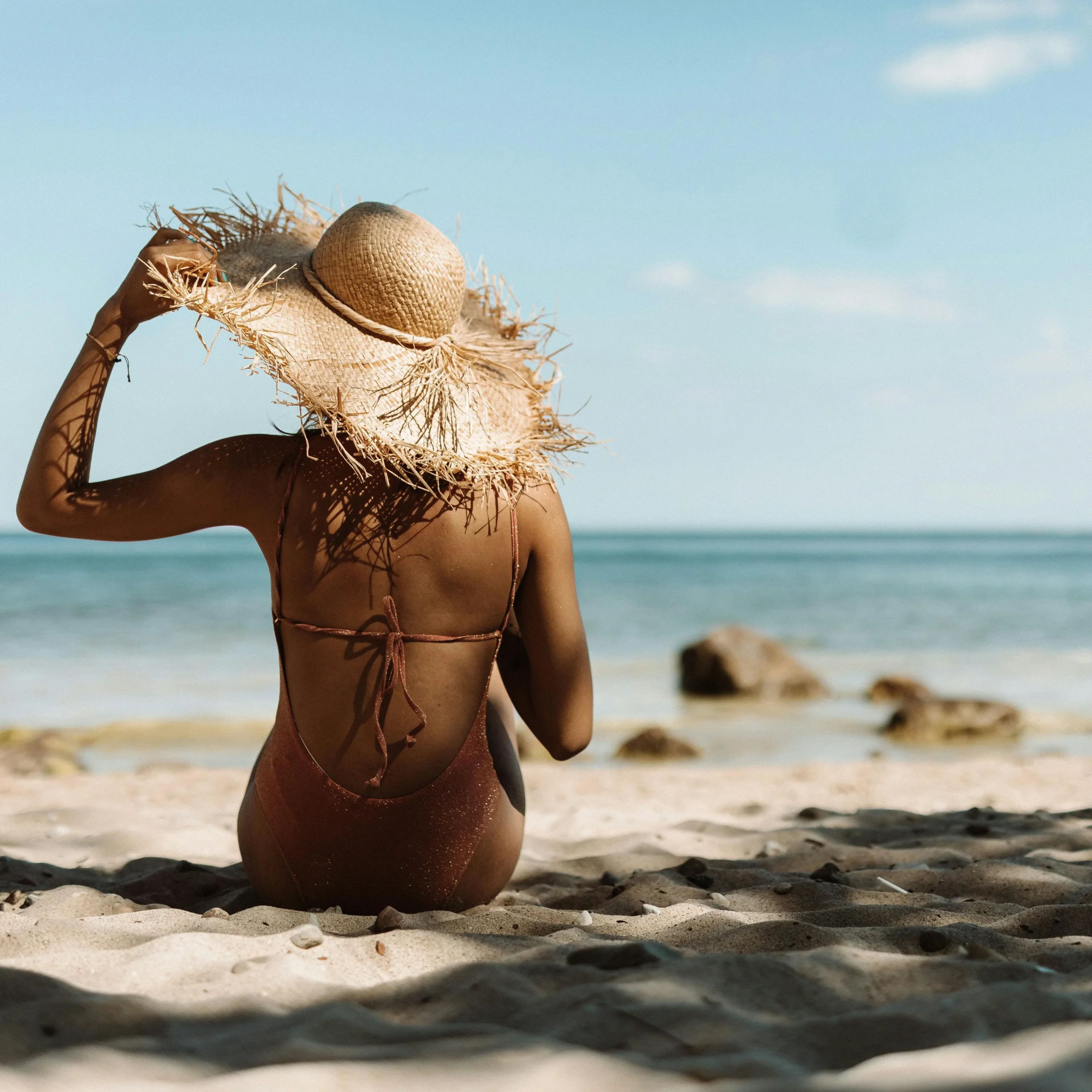 Woman Relaxing on a Sandy Beach with Sun Hat