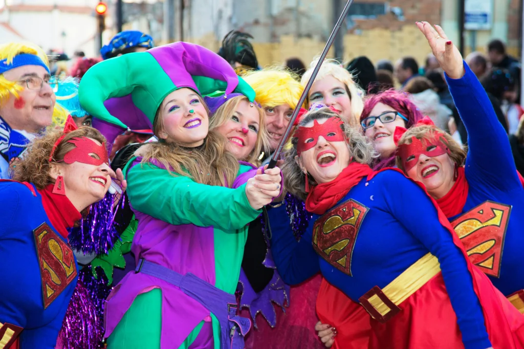 Personas disfrazadas con trajes coloridos y máscaras tomando un selfie en una celebración de carnaval en Barcelona.