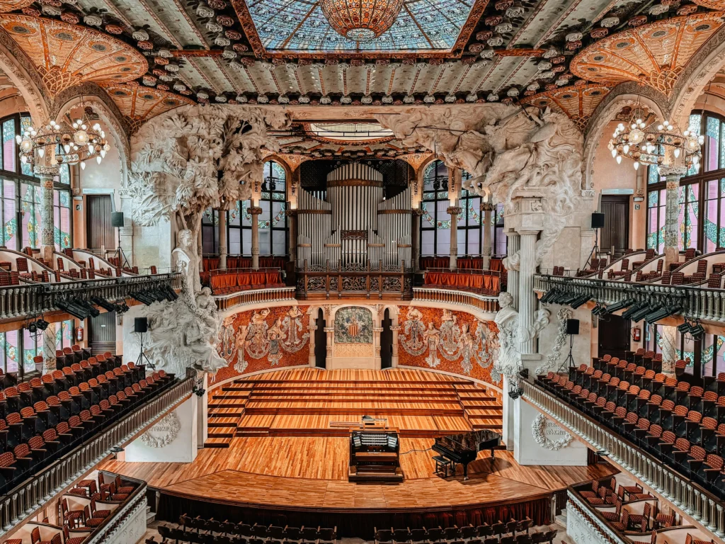 Interior del Palau de la Música Catalana en Barcelona, con detalles arquitectónicos modernistas, asientos elegantes y un impresionante techo decorado.