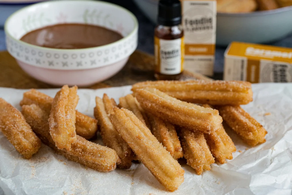 Plato de churros espolvoreados con azúcar acompañados de un tazón de chocolate caliente, un clásico dulce de invierno en España.