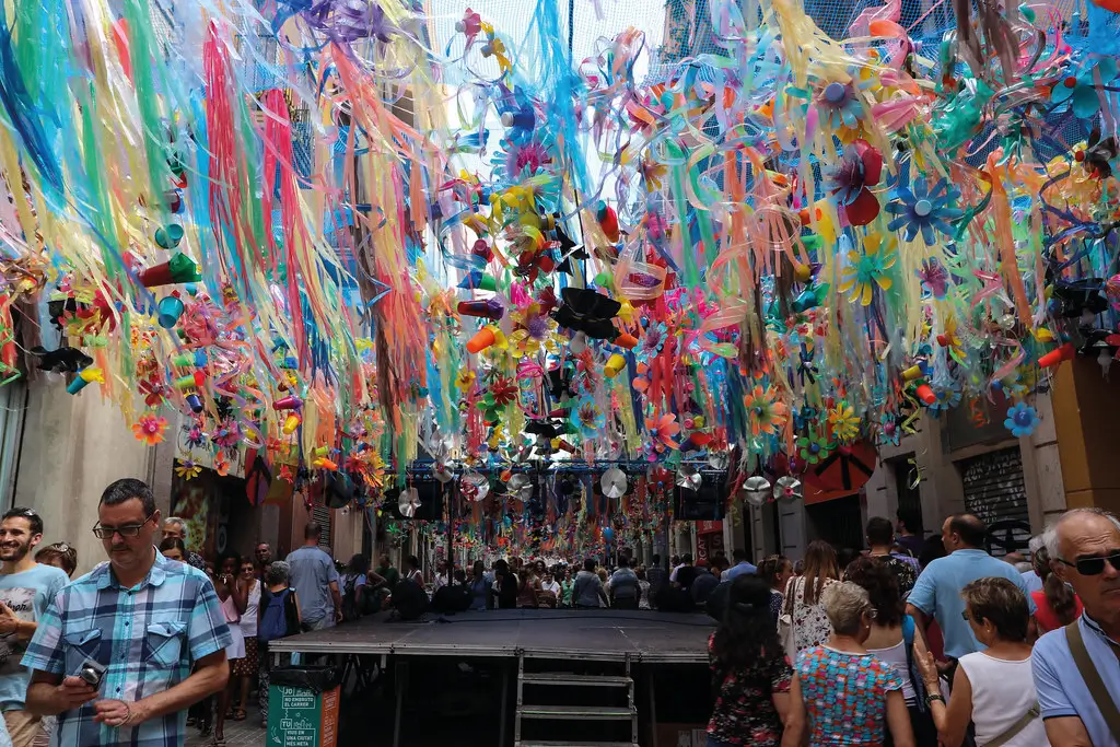 Calle decorada con cintas, flores y elementos reciclados de colores brillantes durante la Festa Major de Gràcia, una celebración tradicional del barrio de Gràcia en Barcelona, repleta de creatividad y ambiente festivo.
