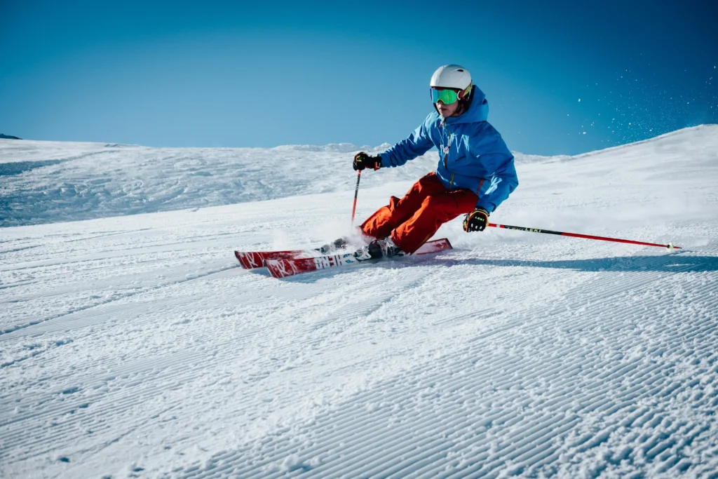 Persona esquiando en una pista de nieve perfectamente cuidada bajo un cielo azul, representando actividades de invierno cerca de Barcelona.