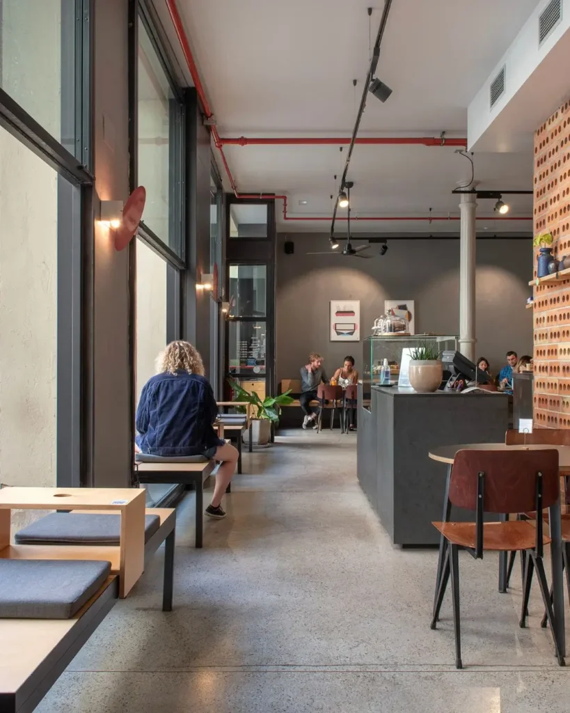 Interior moderno y luminoso de Federal Café en Barcelona, con mesas de madera, sillas minimalistas y clientes disfrutando del brunch.