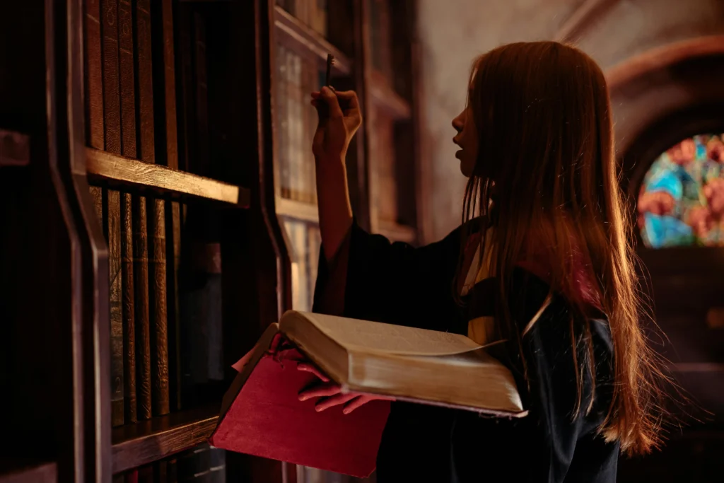 Joven vestida con túnica leyendo un libro antiguo, simbolizando el descubrimiento de los secretos y misterios de Barcelona.