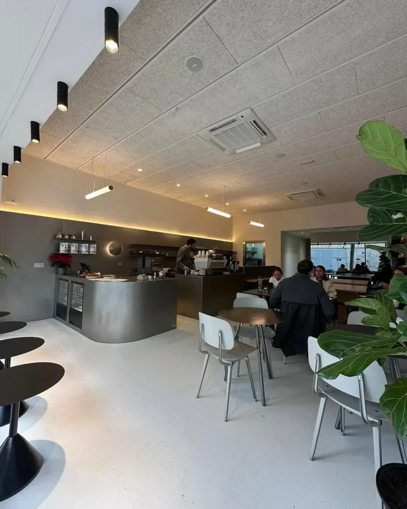 Diseño interior minimalista de Osom Coffee en Barcelona, con tonos grises, líneas modernas y un ambiente sereno para tomar café.