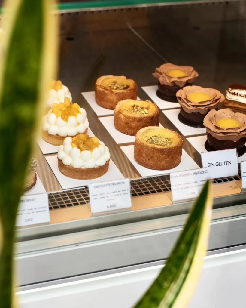 Витрина с тарталетками и мини-пирожными разных вкусов, включая тропические, фисташковые и безглютеновые, аккуратно выставленные в кондитерской Барселоны.