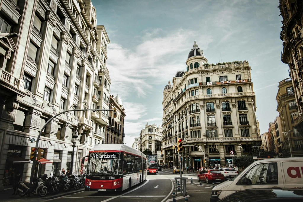 Un autobús urbano con destino Barceloneta avanza por una calle del centro de Barcelona, rodeado de edificios históricos, tráfico y peatones en un ambiente urbano dinámico.