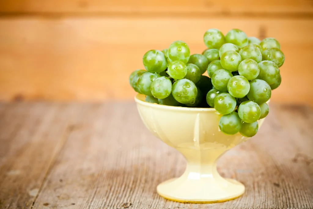 Racimo de uvas verdes en un cuenco, símbolo de la tradición española de comer doce uvas en Nochevieja para atraer la buena suerte.
