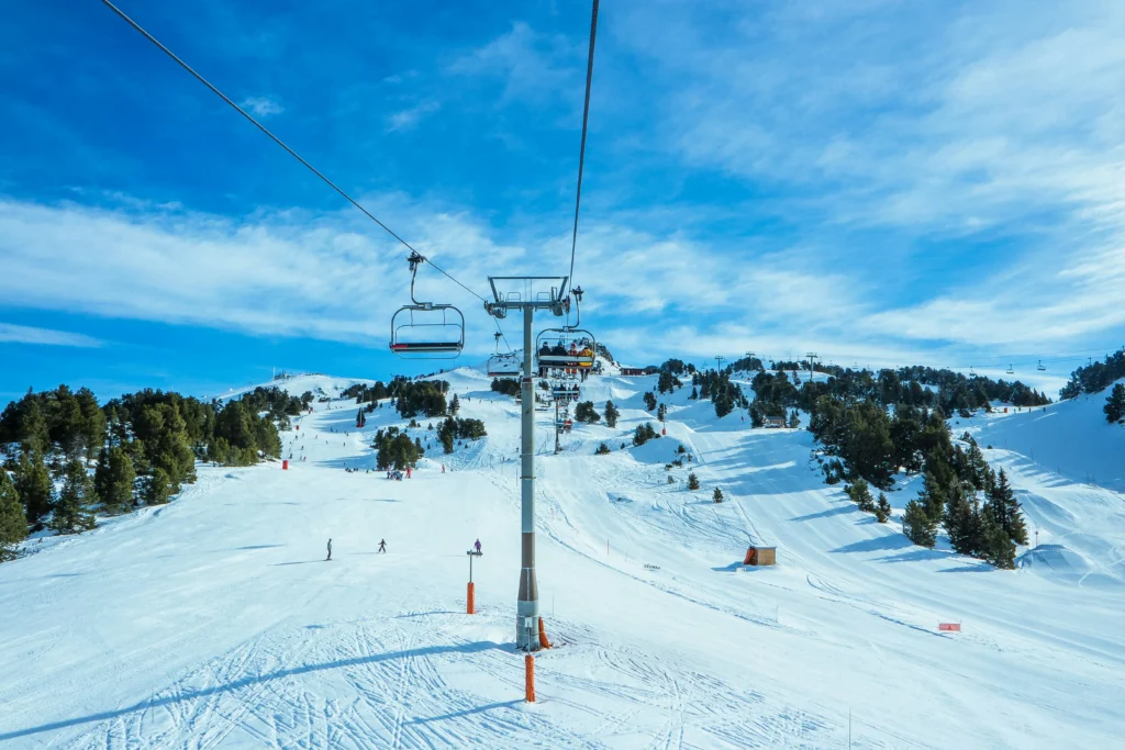 Vista panorámica de una estación de esquí con remonte, pistas nevadas y esquiadores en un día soleado de invierno