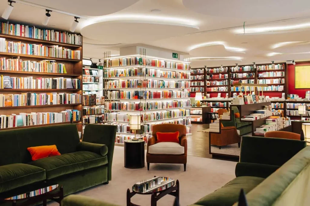 Interior de una librería moderna en Barcelona, con estanterías llenas de libros, sillones cómodos y un ambiente tranquilo y luminoso pensado para la lectura y el descanso.