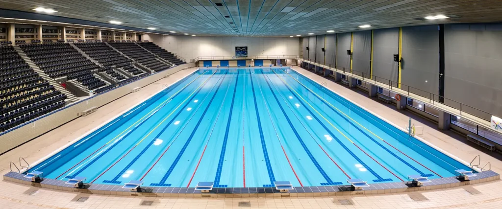 Piscina olímpica cubierta de 50 metros con múltiples carriles de natación y gradas, ideal para entrenamientos y competiciones en Barcelona