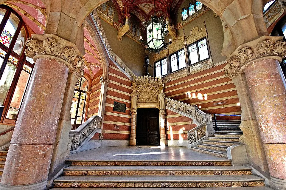 Vestíbulo interior del Hospital de Sant Pau en Barcelona con escaleras de mármol, columnas ornamentadas y detalles arquitectónicos de estilo modernista.
