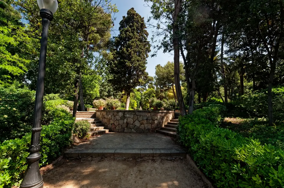 Sendero rodeado de vegetación en los Jardines de Laribal en Montjuïc, Barcelona, con escaleras de piedra, árboles y un entorno tranquilo al aire libre