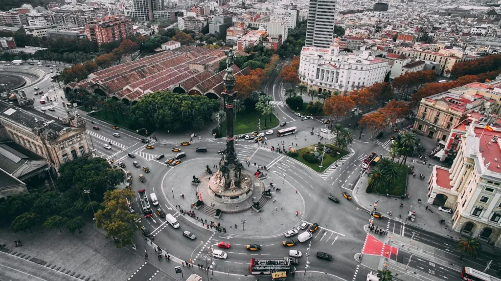 Vista aérea de la Plaza Colón en Barcelona con el monumento a Cristóbal Colón, tráfico alrededor de la rotonda y edificios históricos en el entorno