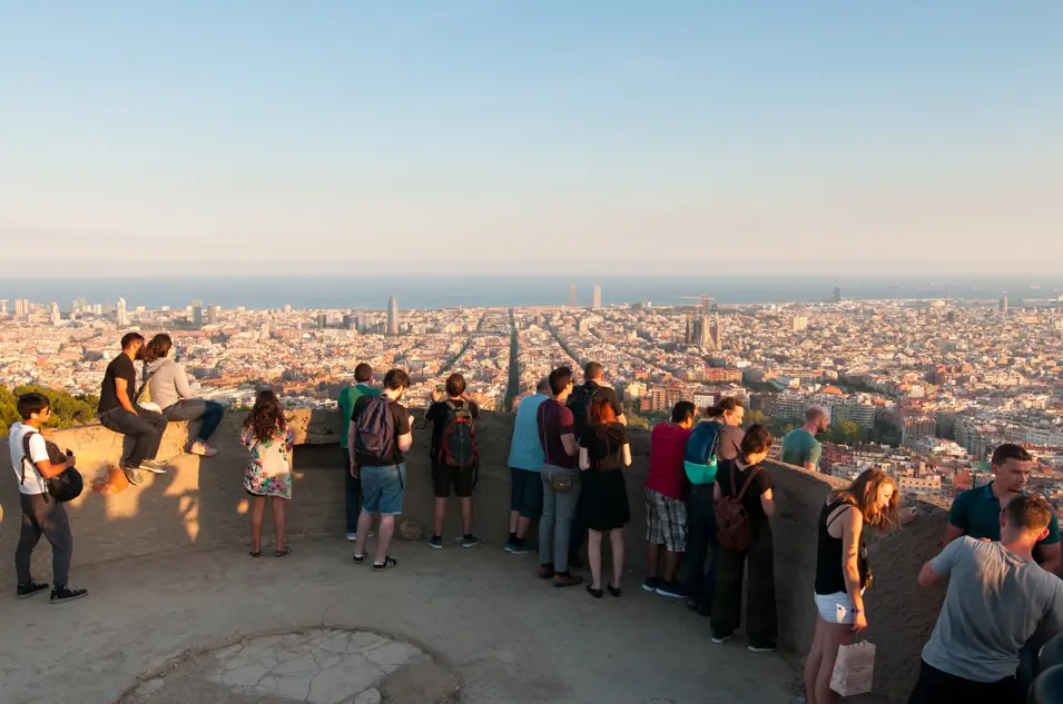 Turistas disfrutando de las vistas panorámicas de Barcelona desde los Búnkers del Carmel al atardecer.