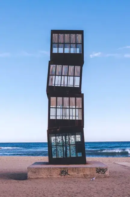 Escultura L'Estel Ferit de Rebecca Horn situada en la playa de la Barceloneta, una obra de arte contemporáneo formada por cubos metálicos apilados frente al mar Mediterráneo en Barcelona.