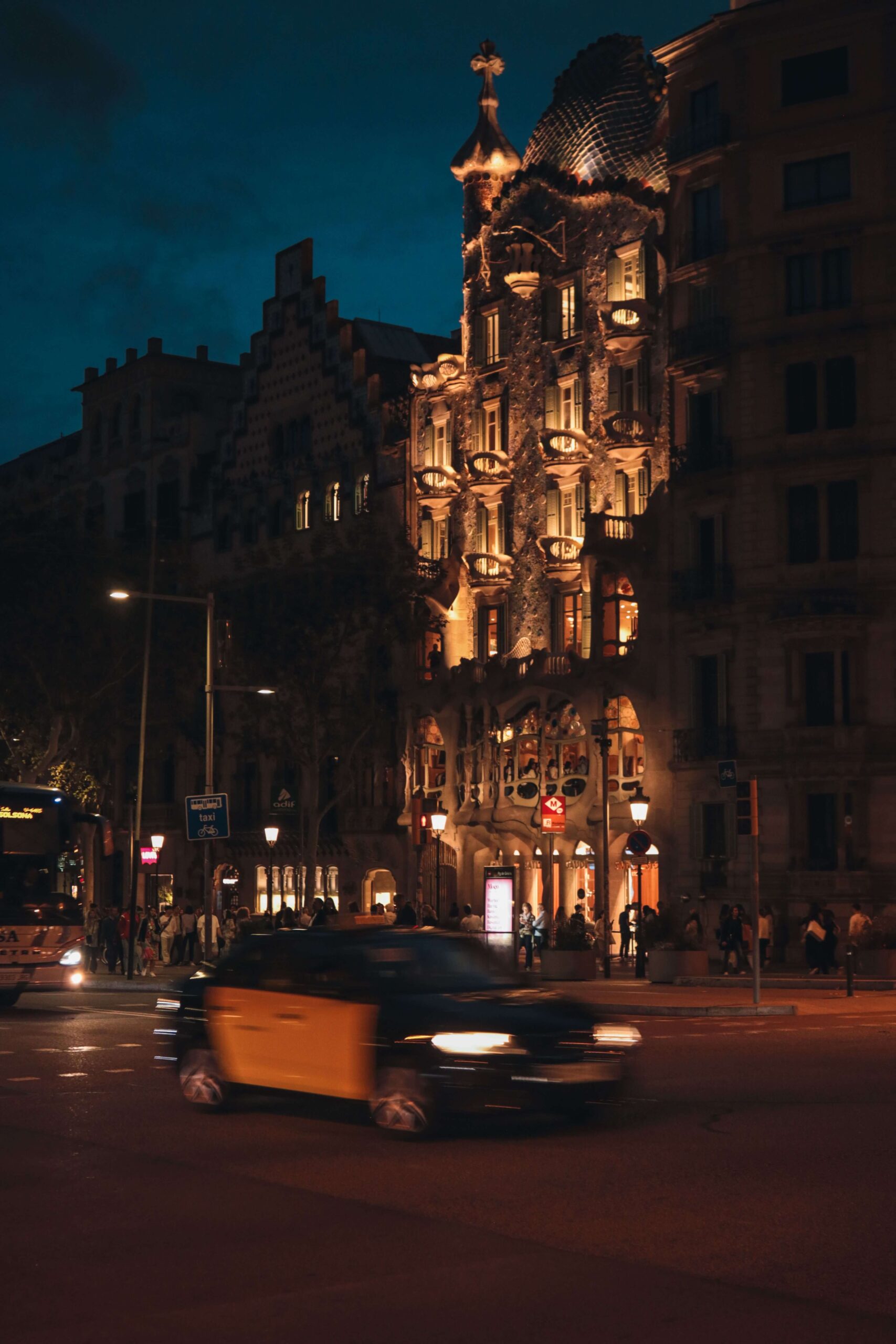 Casa Batlló de noche con un taxi pasando por delante 