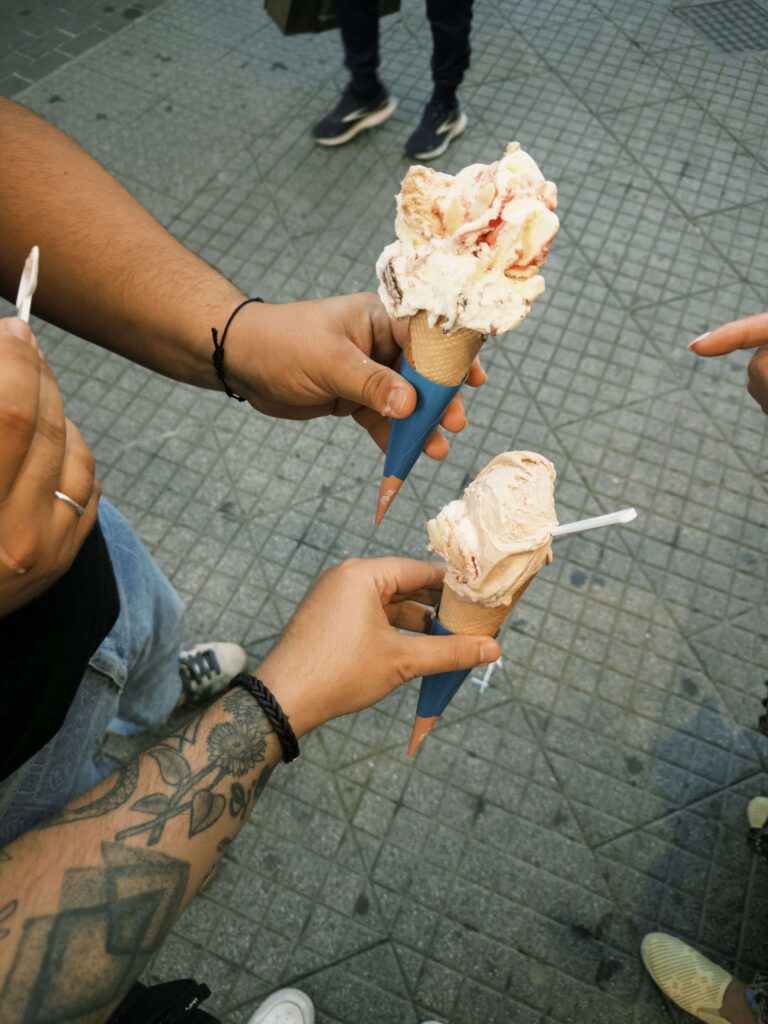 Two hands holdings ice cream cones.
