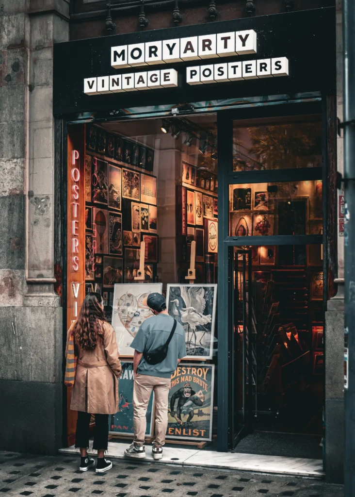 Entrée de Moryarty Vintage Posters avec des visiteurs découvrant des œuvres et des affiches vintage à Barcelone.