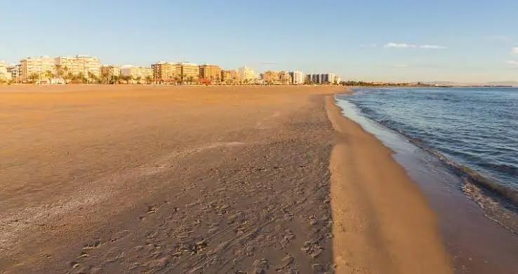 Wide sandy shoreline at Nova Mar Bella Beach in Barcelona, offering a peaceful Mediterranean setting with calm waters and views of the city's coastline.