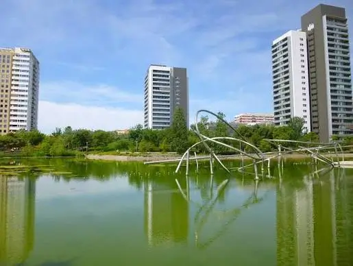 Lake and iconic metal sculptures at Parc de Diagonal Mar in Barcelona, surrounded by modern residential buildings and green spaces.