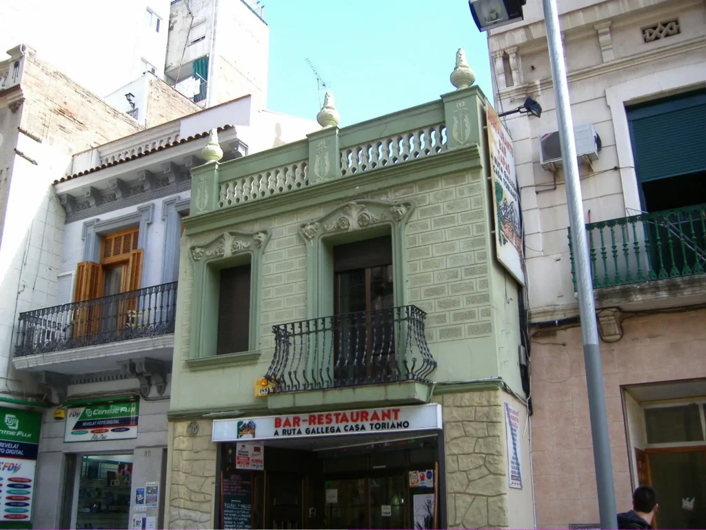Traditional residential building with a pale green façade and wrought-iron balcony in Barcelona's El Clot neighbourhood.
