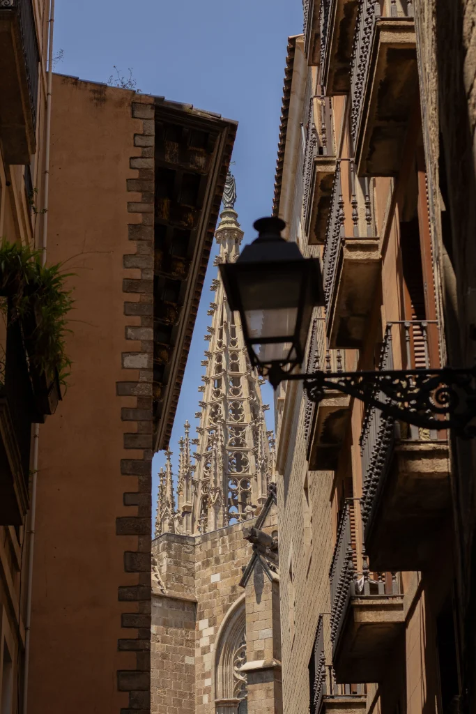 View of Barcelona Cathedral rising between the narrow historic streets and balconies of the Gothic Quarter.