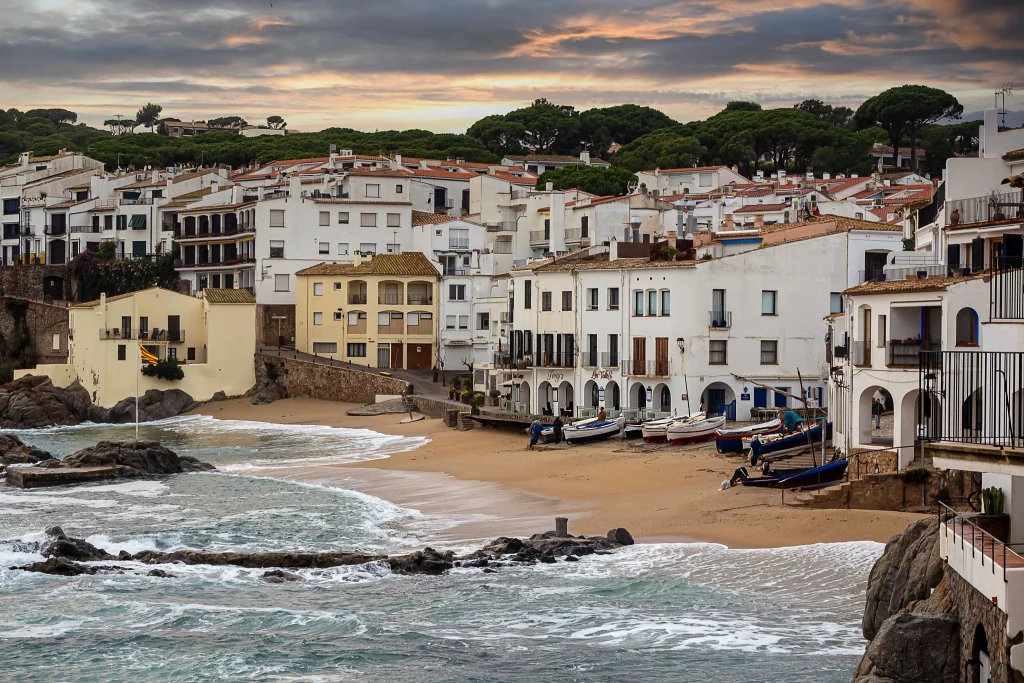 Traditionelle Fischerboote und weiß getünchte Häuser am Strand von Calella de Palafrugell an der Costa Brava.