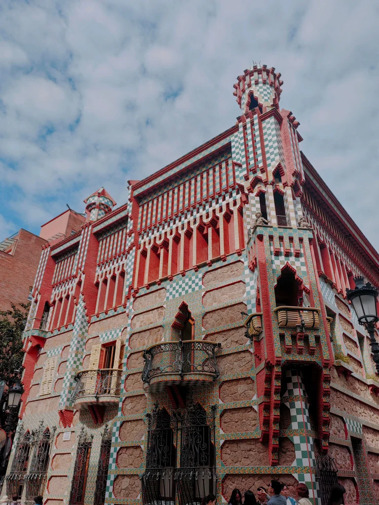 Colourful façade of Casa Vicens in Barcelona, featuring its distinctive red brick and green and white ceramic tiles.