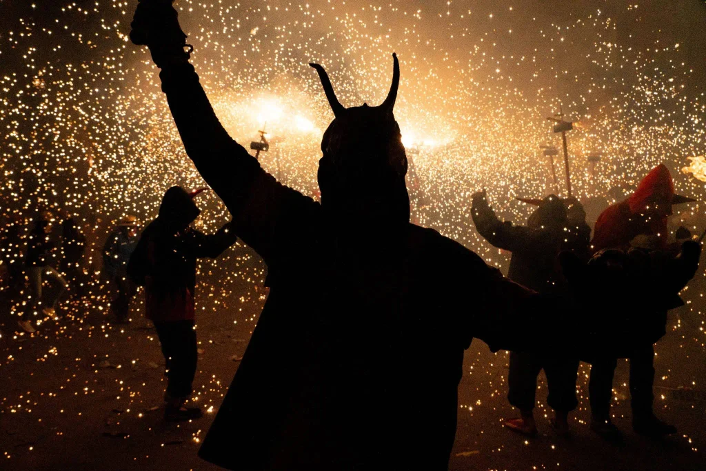 Correfoc performers surrounded by sparks during a traditional fire run celebration in Barcelona.