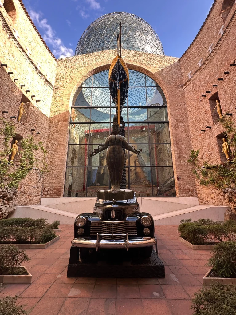 Innenhof des Dalí-Theater-Museums in Figueres mit einer surrealistischen Skulptur unter der ikonischen Glaskuppel.