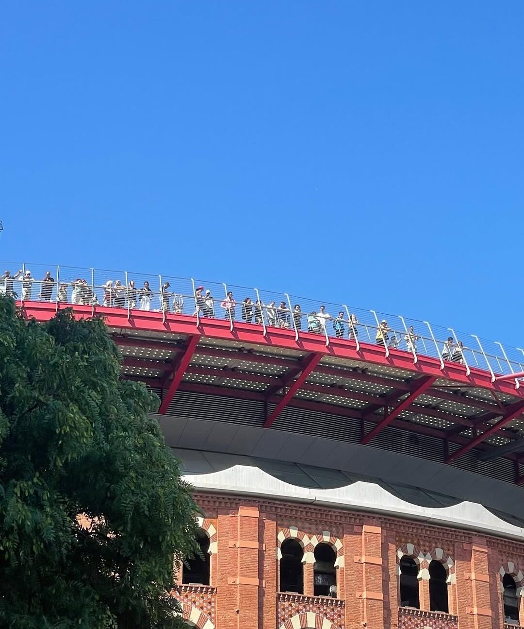 Visitors walking along the rooftop terrace of Las Arenas in Barcelona under a clear blue sky.