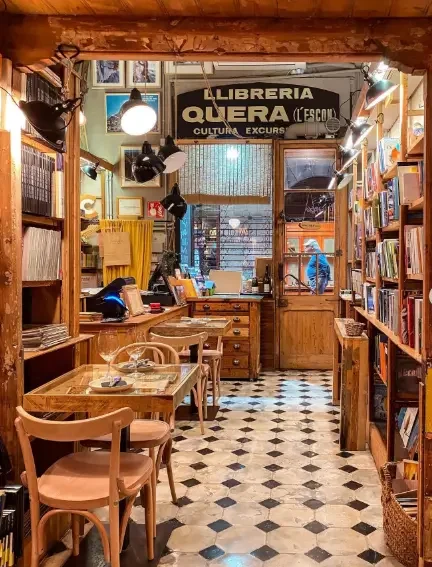 Interior of Llibreria Quera, a historic bookshop in Barcelona, with wooden bookshelves, reading tables and traditional décor.