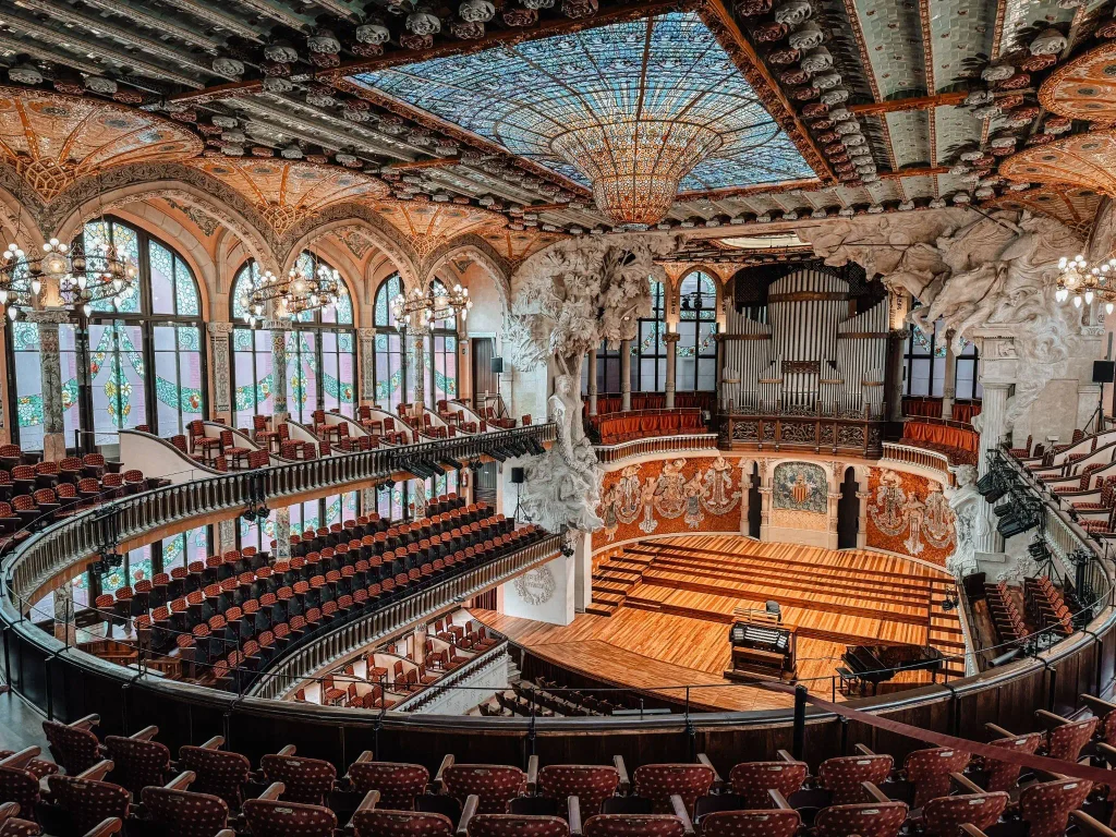 Interior of the Palau de la Música Catalana in Barcelona, featuring its stained-glass ceiling, ornate architecture and concert stage.
