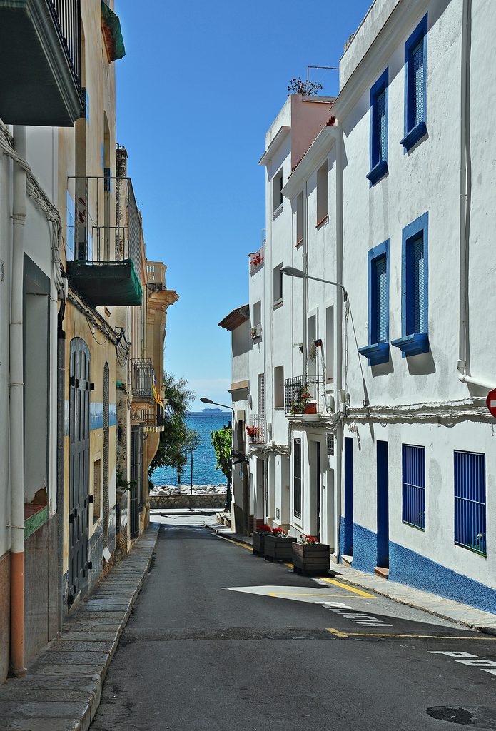 Traditionelle Straße mit weiß getünchten Häusern, die in Sant Pol de Mar in Katalonien zum Mittelmeer führt.