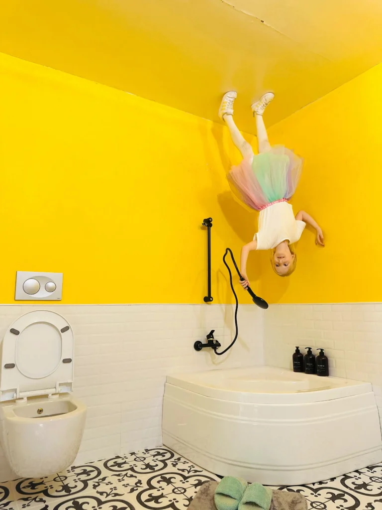 Niño posando boca abajo en una colorida sala amarilla de un museo interactivo de Barcelona.