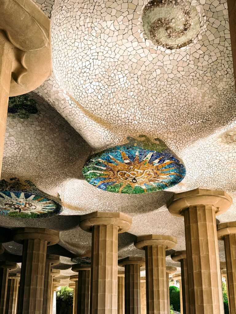 Techo de mosaico de colores y columnas de piedra en la Sala Hipóstila del Park Güell de Barcelona.